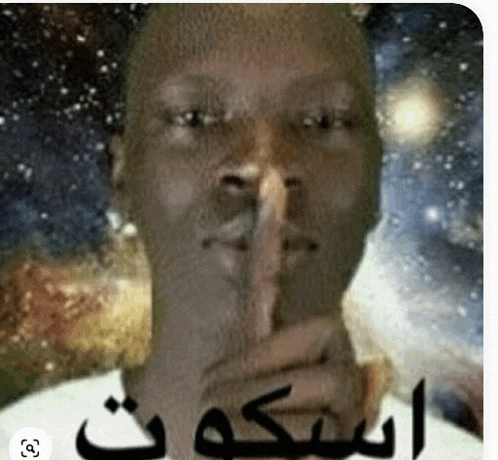 a man is holding his finger to his mouth with arabic writing behind him