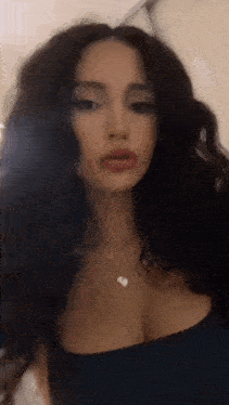 a woman with long dark hair is wearing a necklace and a blue top .