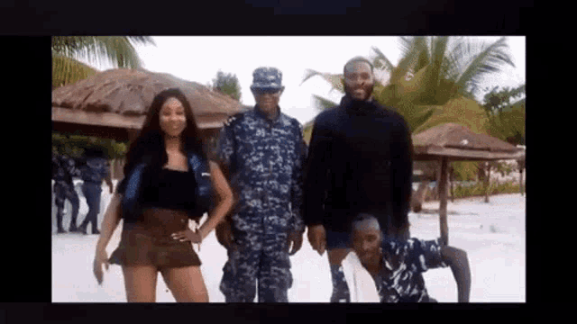 a man in a military uniform is standing next to a woman and a man on the beach .