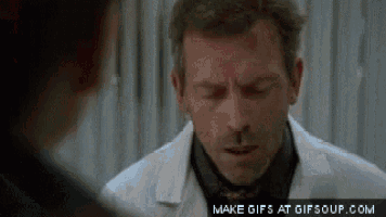 a man in a white coat and tie is talking to another man in a black shirt .