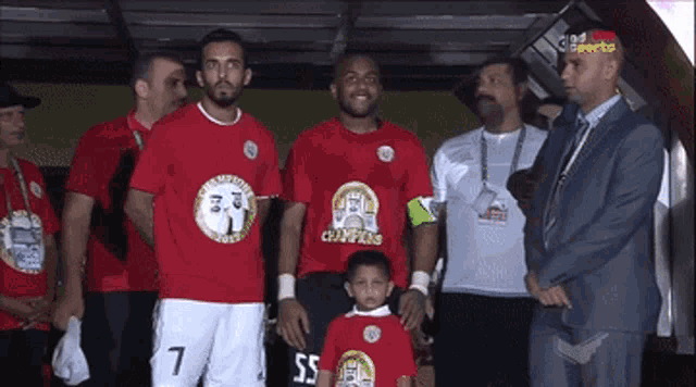 a group of soccer players are posing for a photo with a little boy wearing a shirt that says champions