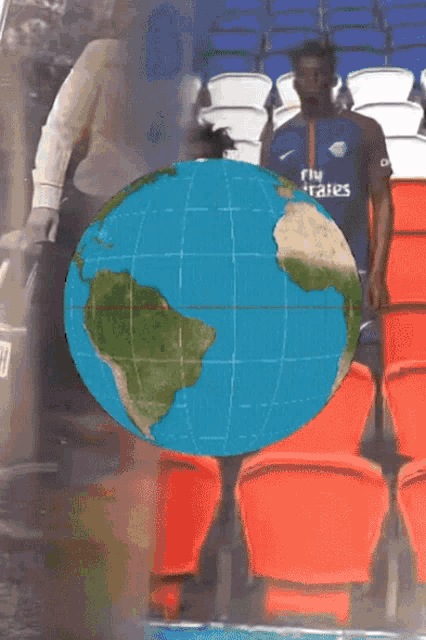 a globe with a car in the background and people walking behind it