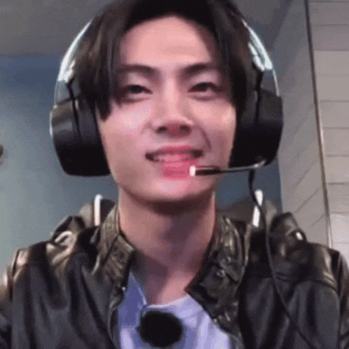 a man wearing headphones and a microphone is smiling .