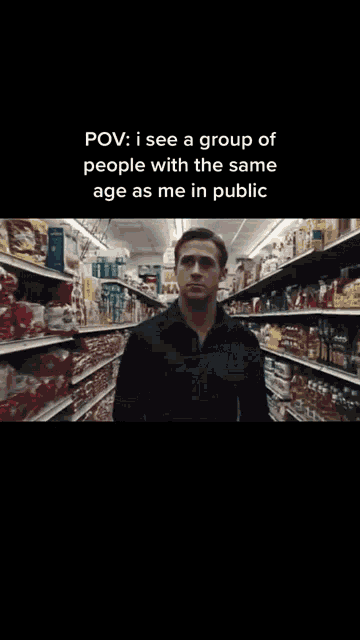 a man in a black shirt is standing in front of a refrigerator in a grocery store ..