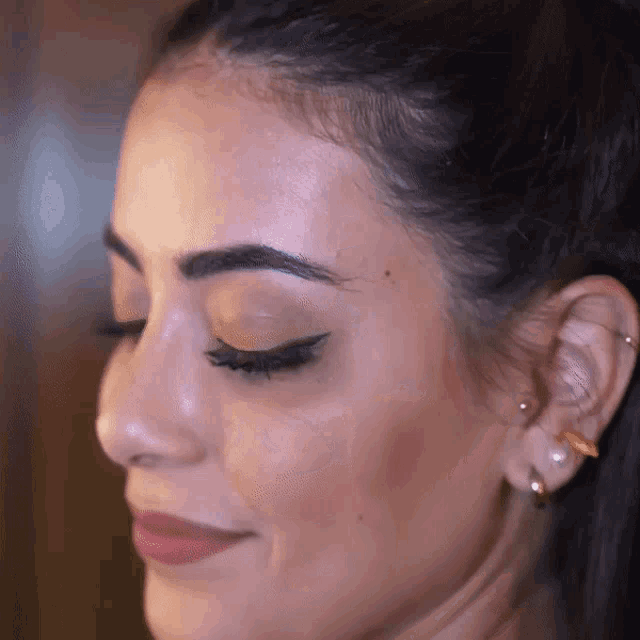 a close up of a woman 's face with her eyes closed and earrings on