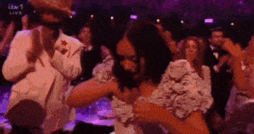 a man in a cowboy hat is dancing with a woman in a white dress in a crowd .