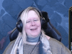a woman is wearing headphones and smiling while sitting in a chair .