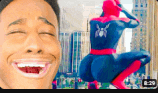 a man is laughing in front of a spider man statue .