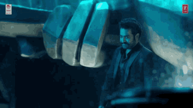 a man in a suit is standing in front of a giant fist with a red t on the bottom right