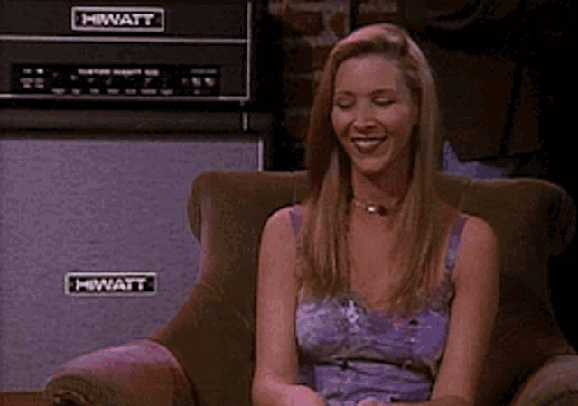 a woman sits in a chair with a hiwatt amplifier in the background