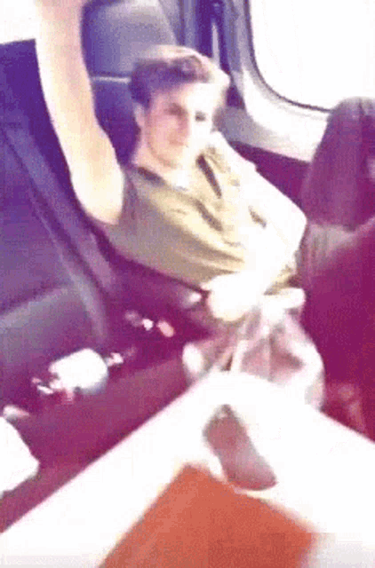 a man is sitting in the back seat of an airplane with his arm up in the air .