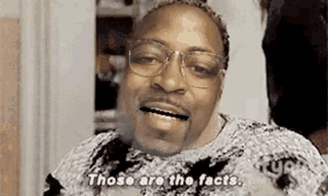 a man wearing glasses is smiling and saying `` those are the facts . ''