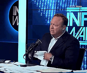 a man in a suit is talking into a microphone in front of a wall that says ' cnn news '