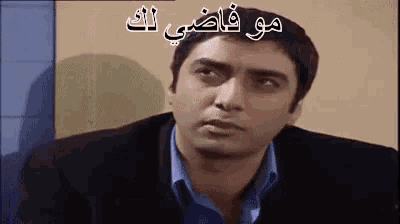 a man in a suit and blue shirt is making a funny face in a video .