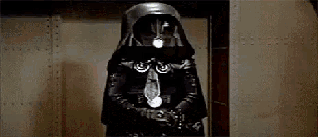 a black and white photo of a person wearing a darth vader mask .