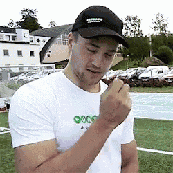 a man wearing a black hat and a white t-shirt is eating a candy bar .