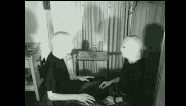 a black and white photo of two men wearing masks talking to each other