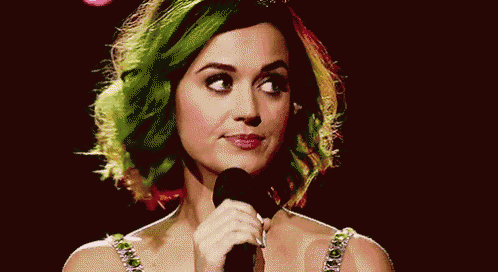 a woman with green hair is holding a microphone and smiling .