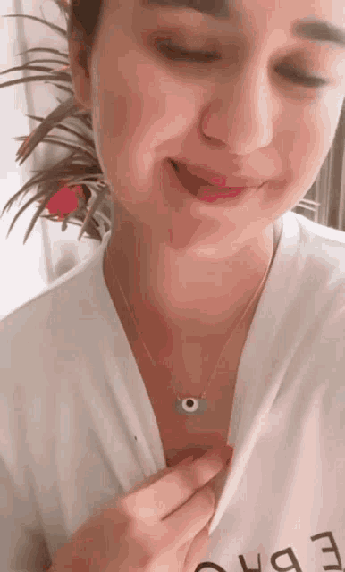 a close up of a woman wearing a necklace with an evil eye on it