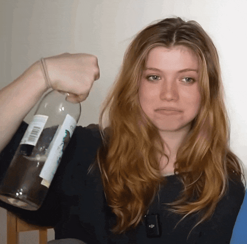 a woman holds up a bottle with a label that says ' a few dollars ' on it
