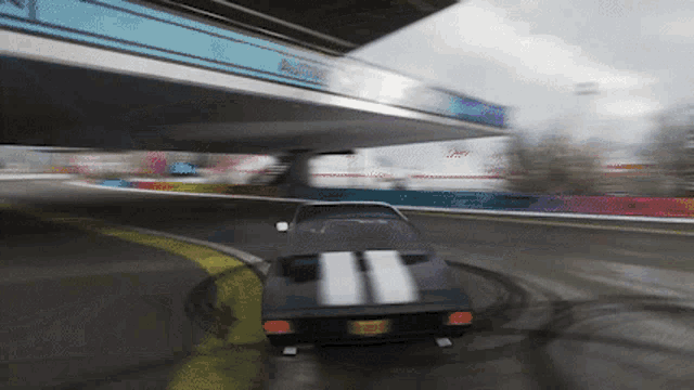 a black car with white stripes on the side is driving on a track