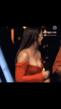 a woman in a red dress is giving a trophy to a man .