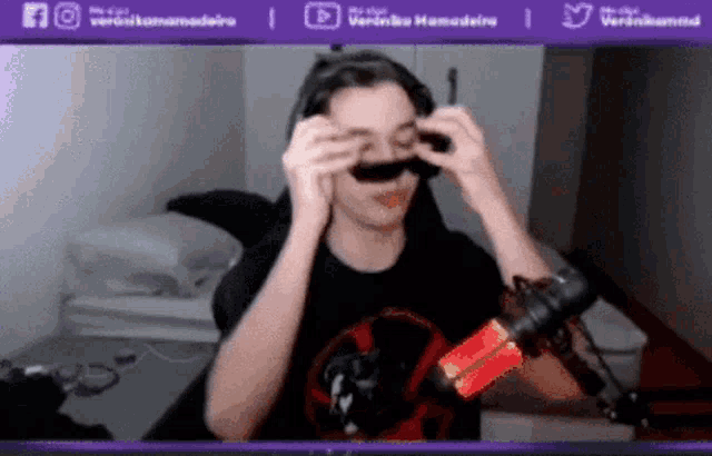 a person is wearing a fake mustache while sitting in front of a microphone ..