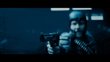 a man in a helmet is holding a gun in front of a cloud of smoke