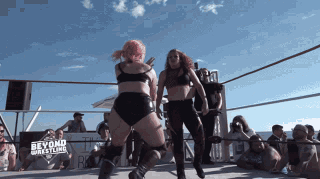 two women in a wrestling ring with a sign that says beyond wrestling on it