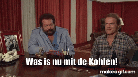 two men are sitting at a desk with the words was is nu mit de kohlen on the screen