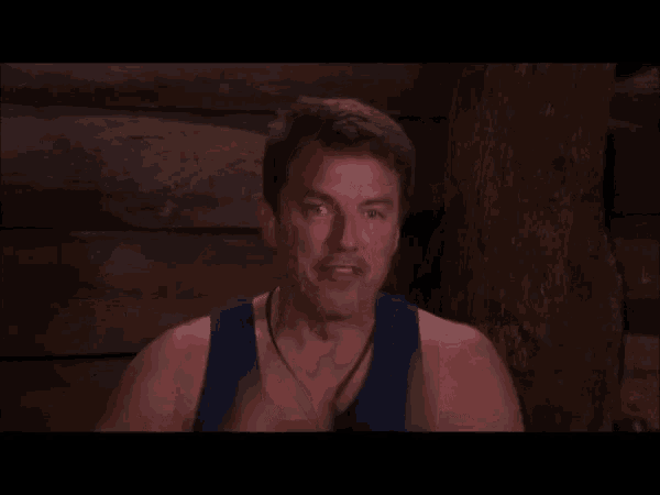 a man in a blue tank top is holding his head in pain