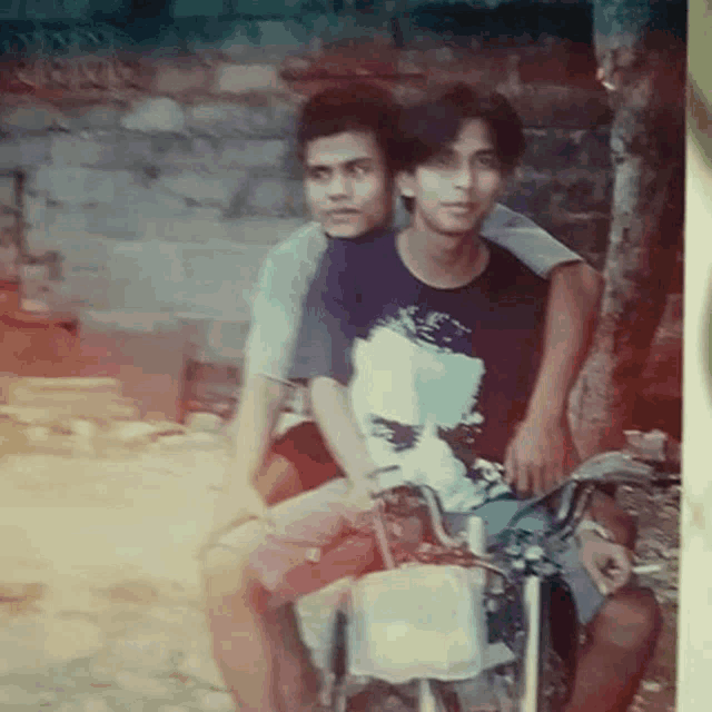 two young men are sitting next to each other on a bike .