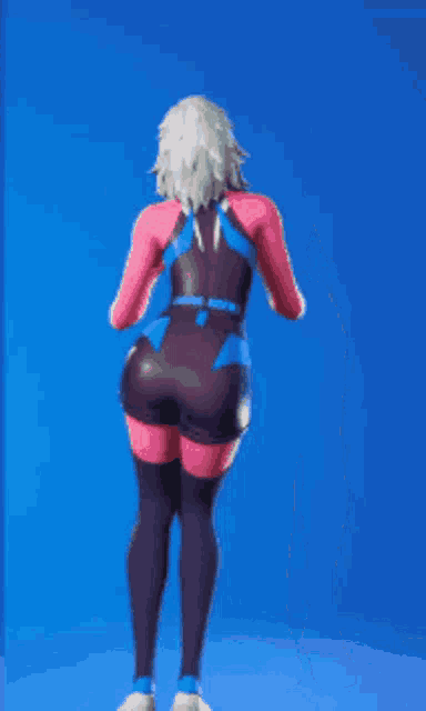 a woman is standing in front of a blue background wearing a pink and blue outfit .