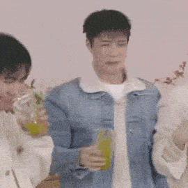 a man in a denim jacket is holding a glass of juice .