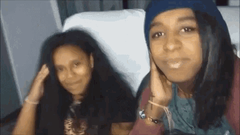 two women are sitting next to each other on a couch .
