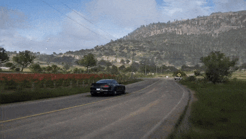 a car is driving down a road in a video game with mountains in the background