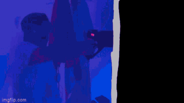 a man holding a gun in a dark room with imgflip.com at the bottom