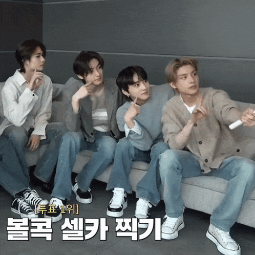 a group of young men are sitting on a couch and one of them is holding a wii controller