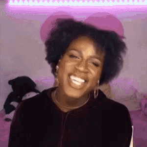 a woman is smiling and making a funny face in front of a pink light .