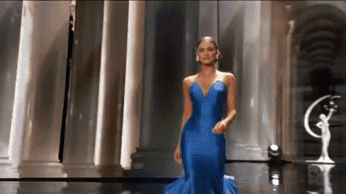 a woman in a blue dress is walking down a runway at a beauty pageant .
