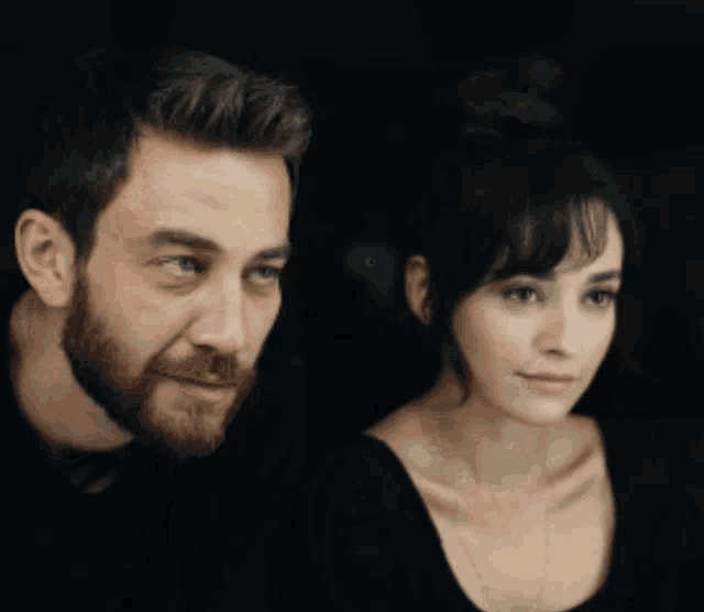 a man with a beard and a woman with dark hair are looking at something