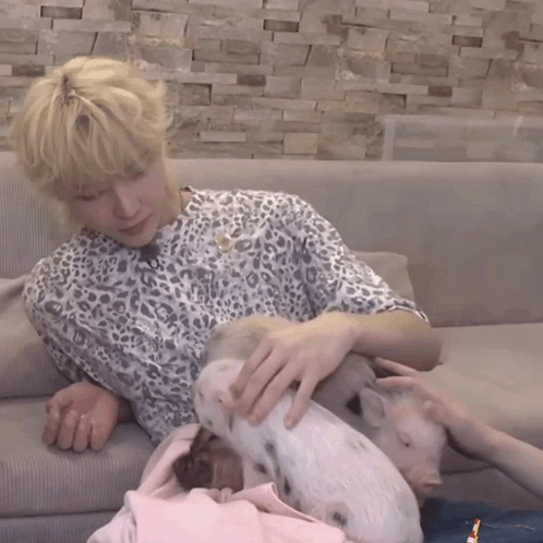 a woman in a leopard print shirt is petting a pig