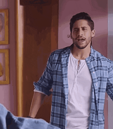 a man with a beard is wearing a plaid shirt and a white shirt .