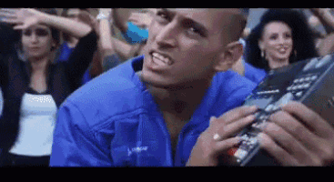 a man in a blue jacket is holding a remote control in front of a crowd