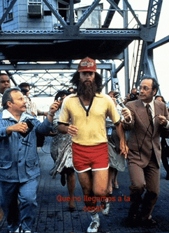 a man with a beard wearing a yellow shirt and red shorts is being interviewed by people