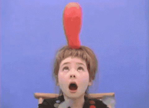 a little girl with a doll on her head looking up