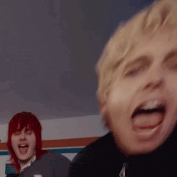 a man with red hair is standing next to another man with blonde hair making a funny face .