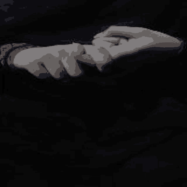 a person is holding another person 's hand in a dark room .