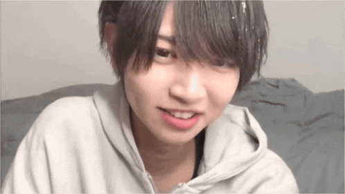 a young boy with short hair is wearing a hoodie and smiling .