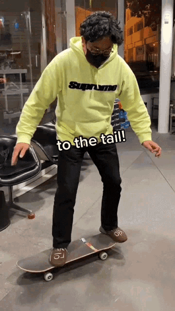 a man wearing a hoodie that says supreme on it is riding a skateboard
